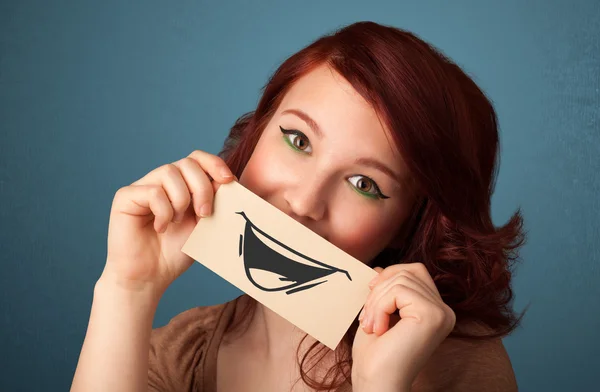 Felice ragazza carina in possesso di carta con divertente disegno smiley — Foto Stock