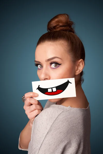 Happy pretty woman holding card with funny smiley — Stock Photo, Image