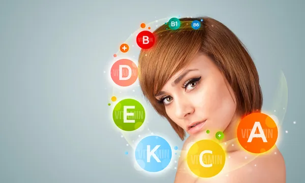 Pretty young girl with colorful vitamin icons and symbols — Stock Photo, Image