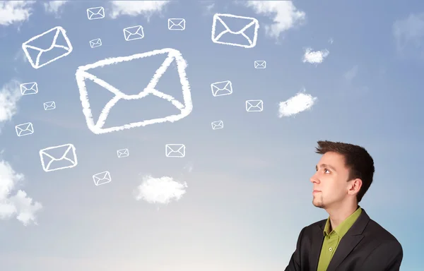 Businessman looking at mail symbol clouds on blue sky — Stock Photo, Image