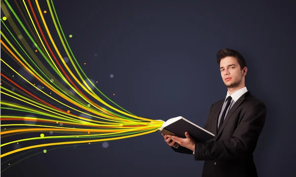 Hombre guapo leyendo un libro mientras líneas coloridas están saliendo —  Fotos de Stock