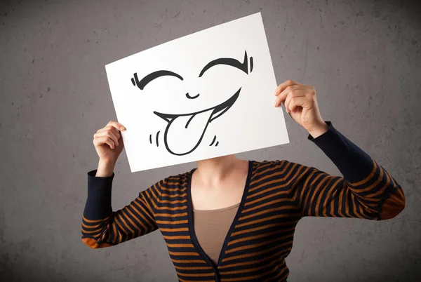 Mujer sosteniendo un papel con cara sonriente lindo en ella delante de él —  Fotos de Stock