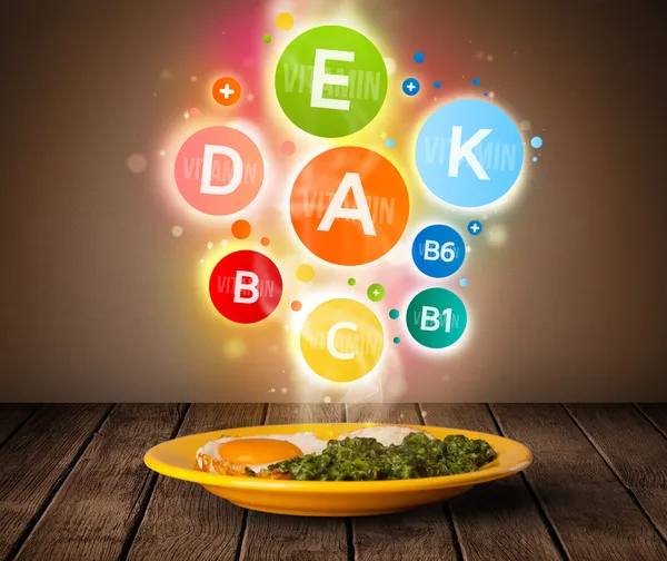 Placa de comida con deliciosa comida y saludables símbolos vitamínicos —  Fotos de Stock