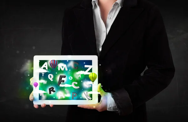 Young person showing tablet with abstract letters and sky — Stock Photo, Image