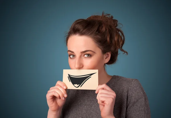 Felice ragazza carina in possesso di carta con divertente disegno smiley — Foto Stock