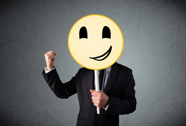 Empresario sosteniendo un emoticono sonriente —  Fotos de Stock