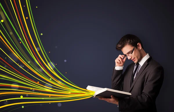Knappe man lezen van een boek terwijl kleurrijke lijnen zijn coming out — Stockfoto