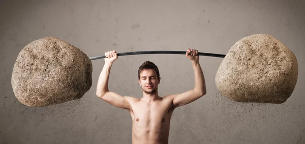 Skinny guy lifting large rock stone weights — Stock Photo, Image