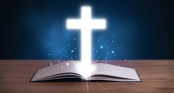 Open holy bible with glowing cross in the middle — Stock Photo, Image