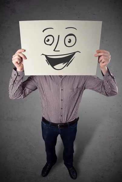 Empresário segurando um papelão com rosto sorridente na frente — Fotografia de Stock