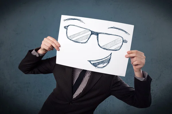 Businessman holding a paper with smiley face in front of his hea — Stock Photo, Image