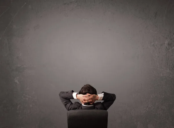 Businessman sitting in front of a wall with copy space — Stock Photo, Image