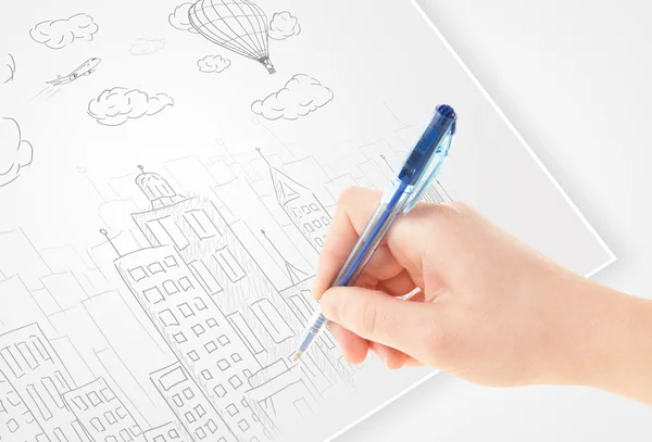 A person drawing sketch of a city with balloons and clouds on a — Stock Photo, Image