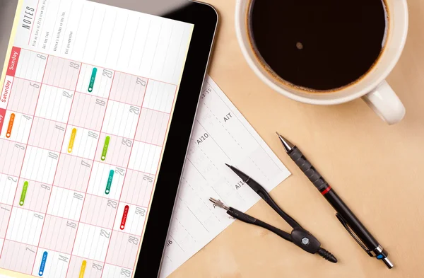 Tablet pc showing calendar on screen with a cup of coffee on a d — Stock Photo, Image