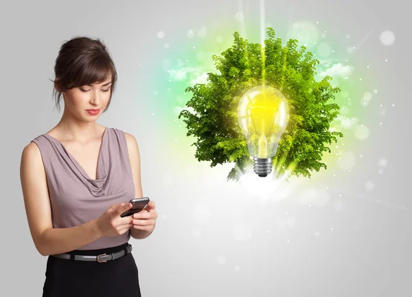 Jong meisje presenteren idee gloeilamp met groene boom — Stockfoto