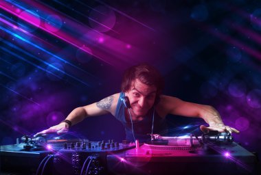 Young DJ playing on turntables with color light effects clipart