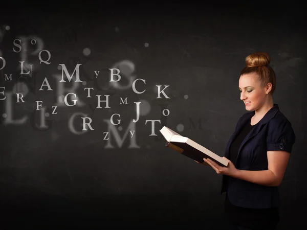 Junge Frau liest ein Buch mit Buchstaben des Alphabets — Stockfoto