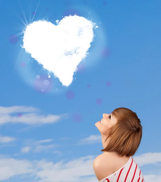 Linda chica mirando a la nube blanca del corazón en el cielo azul — Foto de Stock