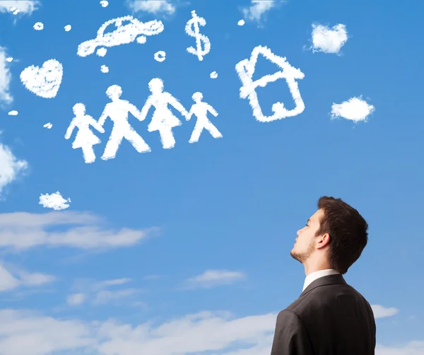 Businessman daydreaming with family and household clouds — Stock Photo, Image