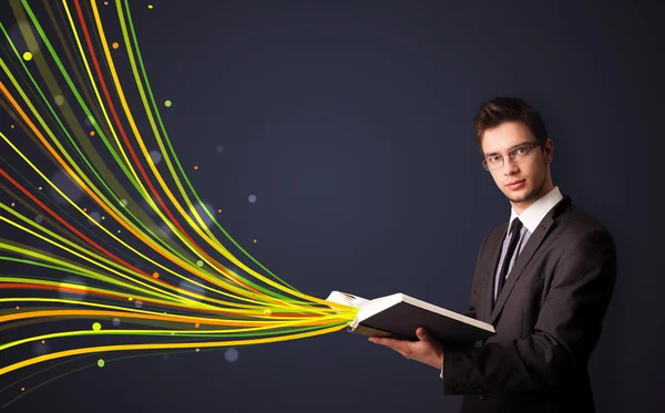 Hombre guapo leyendo un libro mientras líneas coloridas están saliendo — Foto de Stock