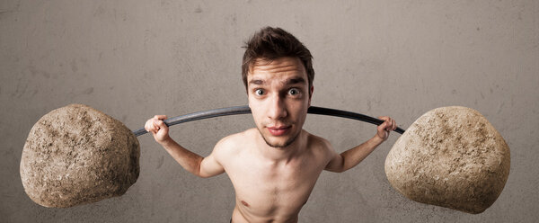 skinny guy lifting large rock stone weights