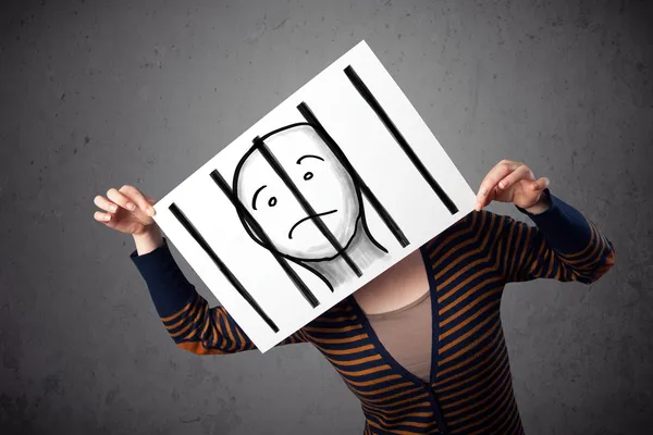 Woman holding a paper with a prisoner behind the bars on it in f — Stock Photo, Image