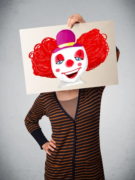 Kobieta trzymając karton z clown na to przed jej hea — Zdjęcie stockowe