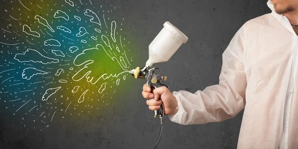 Worker with airbrush gun paints colorful lines and splashes — Stock Photo, Image