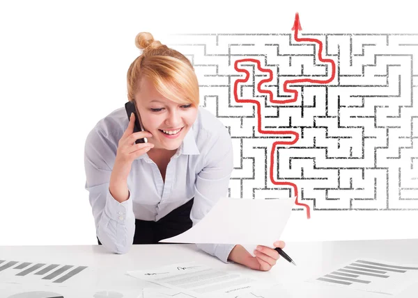 Business woman at desk with labyrinth and arrow — Stock Photo, Image