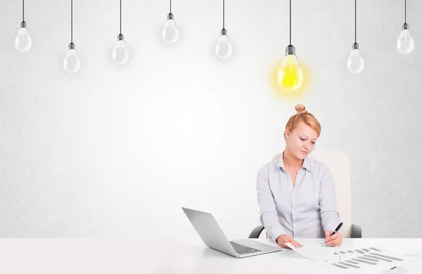 Business woman sitting at table with idea light bulbs — Stock Photo, Image