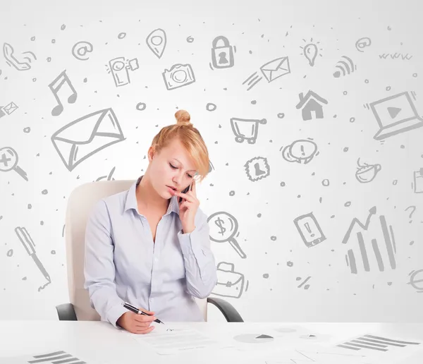 Mujer de negocios sentada a la mesa con iconos de medios dibujados a mano — Foto de Stock