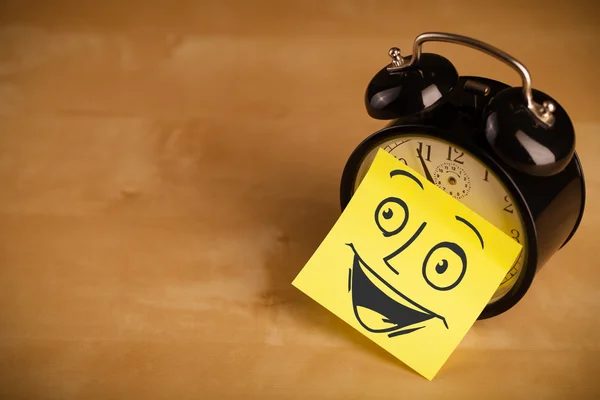 Post-it note with smiley face sticked on clock — Stock Photo, Image