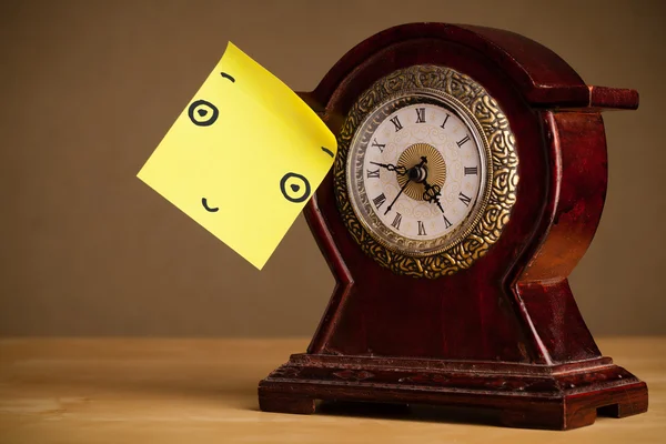 Post-it note with smiley face sticked on a clock — Stock Photo, Image