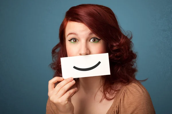 Feliz bonita mujer sosteniendo tarjeta con divertido smiley — Foto de Stock