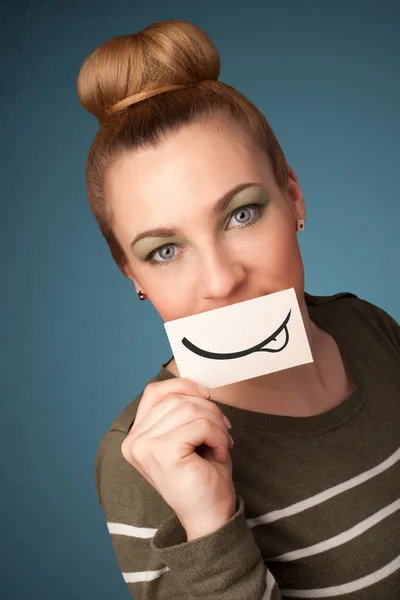 Pretty young girl holding white card with smile drawing — Stock Photo, Image