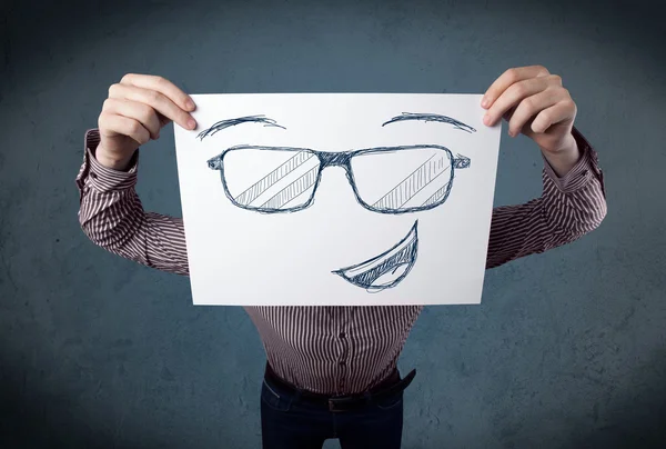 Empresario sosteniendo un papel con la cara sonriente delante de su hea —  Fotos de Stock