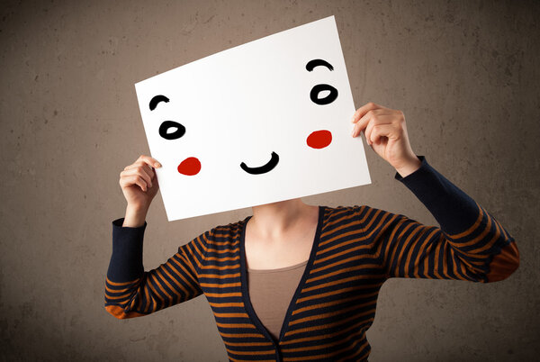 Woman holding a cardboard with a smiley face on it