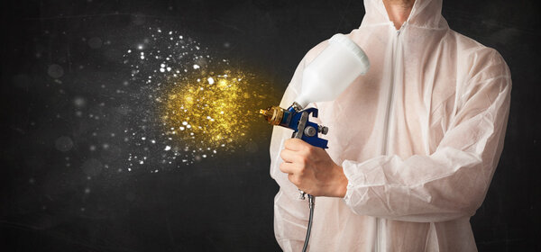 Рабочий с аэрографической живописью с пылающей золотой краской 