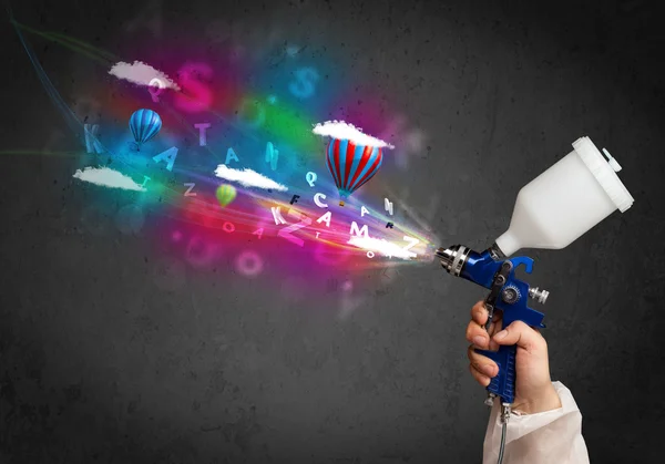 Worker with airbrush and colorful abstract clouds and balloons — Stock Photo, Image