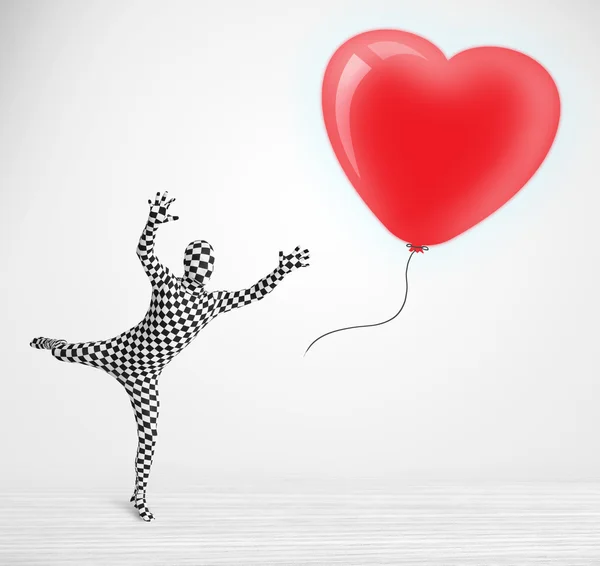 Lindo tipo en traje de cuerpo morpsuit mirando un corazón en forma de globo — Foto de Stock