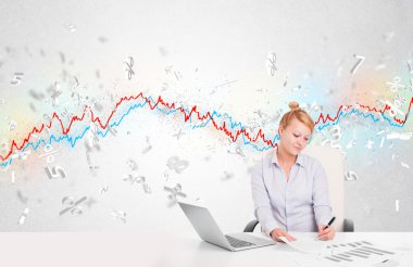 Borsa grafiğiyle masada oturan iş kadını. 