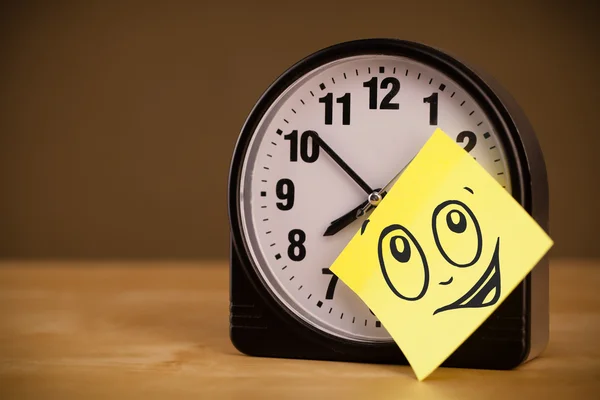 Post-it nota con la cara sonriente pegado en el reloj —  Fotos de Stock