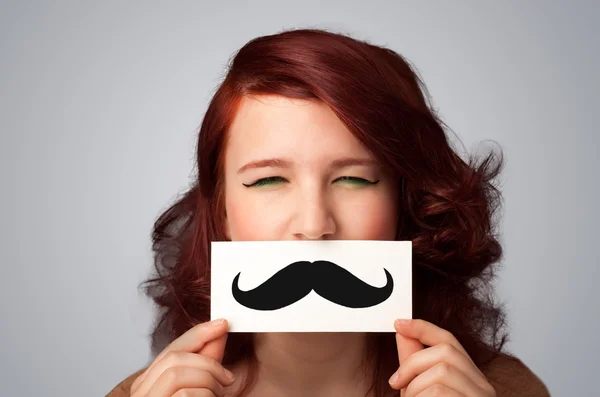 Happy cute girl holding paper with mustache drawing — Stock Photo, Image