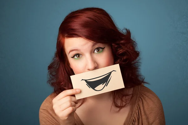 Happy cute girl holding paper with funny smiley drawing — Stock Photo, Image