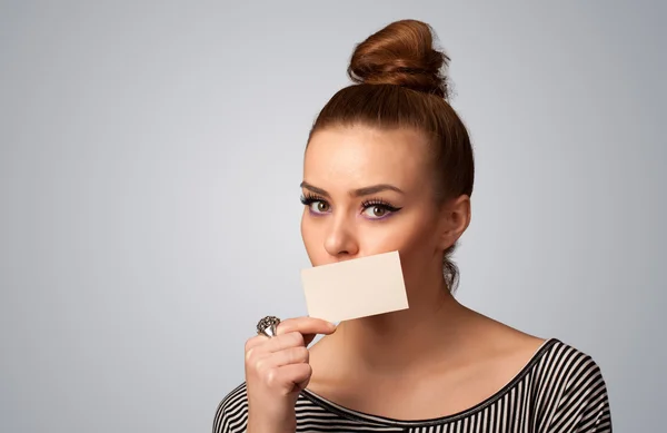 Menina bonito segurando cartão branco na frente de seus lábios com cópia spac — Fotografia de Stock