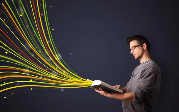 Hombre guapo leyendo un libro mientras líneas coloridas están saliendo — Foto de Stock