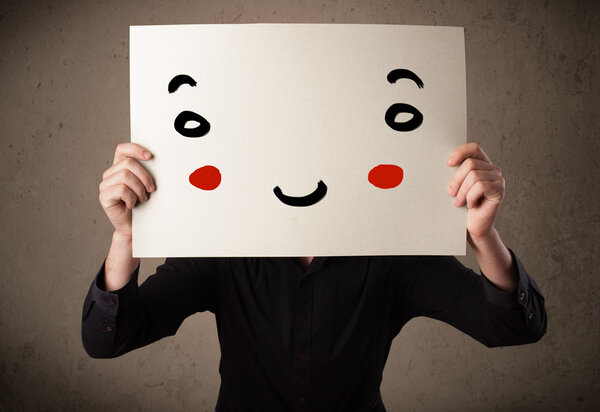 Businessman holding a cardboard with a smiley face on it