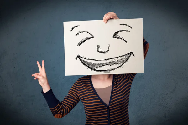 Femme au visage souriant dessiné sur un papier devant sa tête — Photo