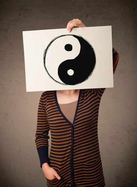 Woman holding a paper with a yin-yang on it in front of her head — Stock Photo, Image