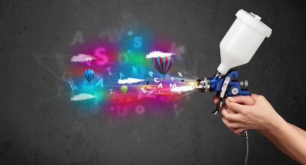 Worker with airbrush and colorful abstract clouds and balloons — Stock Photo, Image